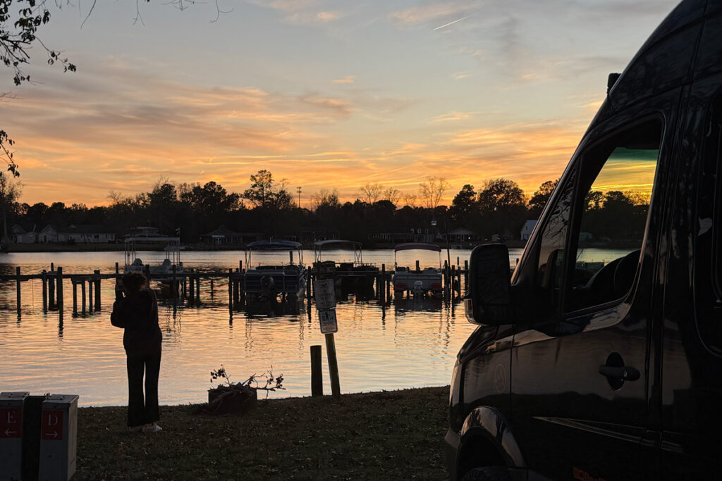 Sunset over Taw Caw Lake with the Deaf Roamer Sprinter van parked at the shoreline.